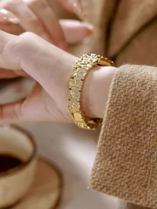 Vista detallada de un reloj de pulsera dorado con textura de lava en la muñeca