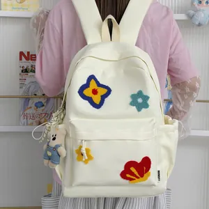 Back view of a student wearing a cute cream backpack with colorful flower patches