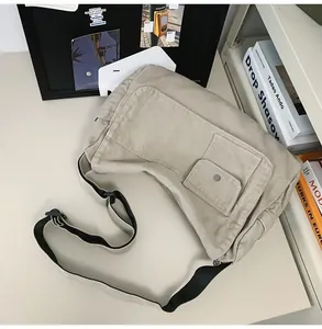 Detail view of a large khaki canvas messenger bag featuring multiple pockets and adjustable strap