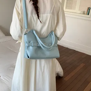 Light blue fashion leather tote bag worn by model in a minimalist indoor setting detail