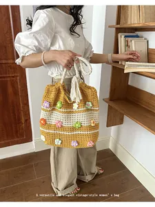 Close-up detail of hand-knitted tote bag with colorful crochet flowers shown in use