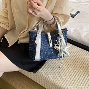 Stylish large blue denim bucket bag featuring silver straps and a decorative star charm
