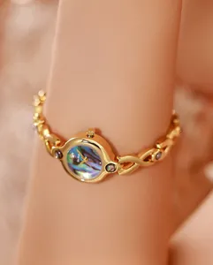 Primer plano de reloj vintage dorado con esfera de nácar de abulón en la muñeca