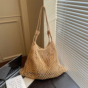 Dettaglio di borsa a tracolla in macramè beige intrecciata a mano con motivo a rete da pesca