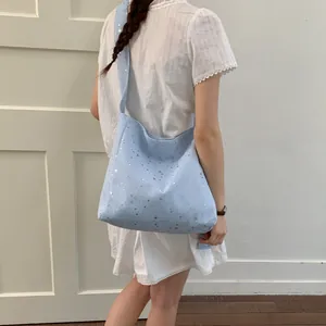 Model wearing a stylish light blue canvas tote bag adorned with sparkling silver stars.