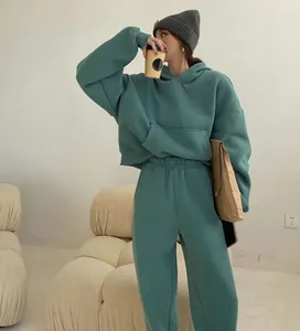 Modelo con un conjunto de dos piezas de sudadera con capucha y pantalón verde azul