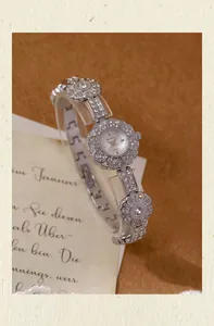 Close-up of silver flower bracelet watch with rhinestone accents and vintage design.