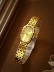 Primer plano de un reloj de lujo en oro con esfera ovalada sobre fondo vintage cálido