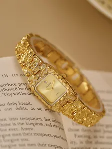 Vista detallada de un reloj de pulsera dorado con textura de lava sobre libro