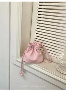 Close-up of a pink drawstring bucket bag displayed on a minimalist white windowsill