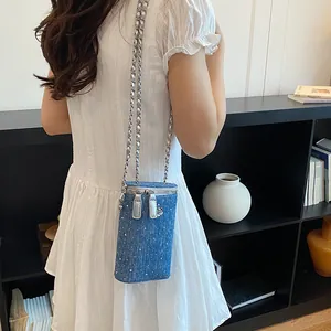 Close-up of a stylish small denim crossbody phone bag featuring a silver chain strap and rhinestones.