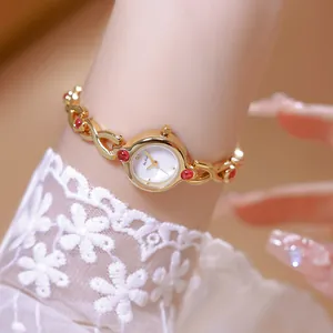 Primer plano de reloj pulsera dorado estilo vintage francés con piedras rojas