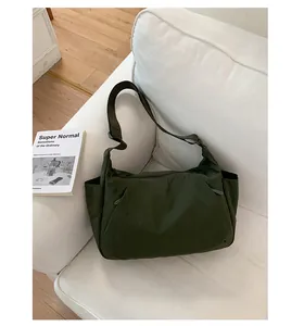 Minimalist large capacity olive green nylon crossbody tote bag for women on a white sofa