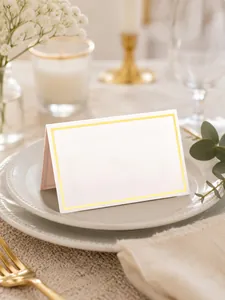 Elegant white wedding place card with gold foil border placed on a luxury dinner plate.