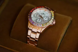 Close-up of rose gold women's watch with rainbow gemstone bezel and sparkling diamond dial