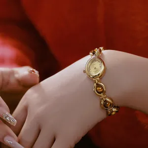 Primer plano de un reloj vintage dorado con una pulsera de piedra ojo de tigre en la muñeca