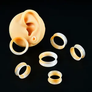 Tunnel auricolari in silicone marmorizzato arancione e bianco con modello di orecchio.