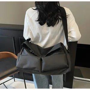 Back view of a large black multi-pocket crossbody bag on a casual female model