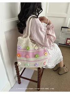 Macro view of handmade crochet tote bag decorated with colorful 3D flowers on woman's shoulder