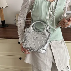 Stylish silver quilted bucket bag with metallic finish and chain strap on model