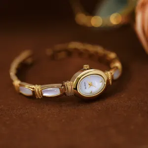 Reloj de pulsera dorado Bee Sister con esfera de nácar sobre fondo de terciopelo marrón