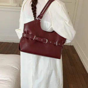 Minimalist dark red leather underarm tote bag featuring a silver buckle belt detail