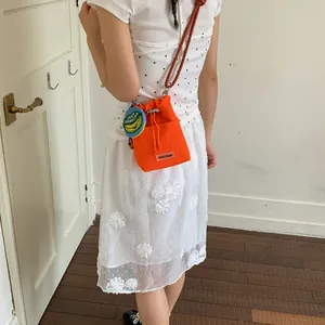 Orange mesh drawstring bucket bag shown on model for a stylish daily commute look