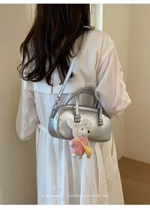 Stylish silver bowling handbag with cute plush bunny charm detail worn by a model