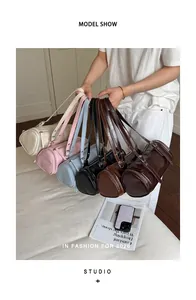 Collection of stylish retro cylinder shoulder bags in various colors held by a model