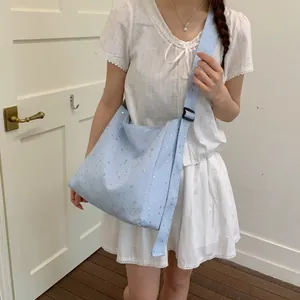 Detail of a model wearing a light blue canvas tote bag with shiny silver sequin stars