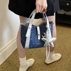Close-up view of a denim bucket handbag with silver accents and decorative star.