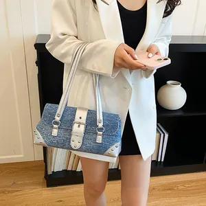 Detailed view of stylish denim shoulder bag featuring silver studs and metallic trim