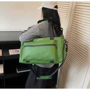 Woman carrying a green large capacity travel duffle bag with a shoulder strap