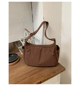 Large capacity brown nylon crossbody tote bag on a wooden countertop in a kitchen setting.
