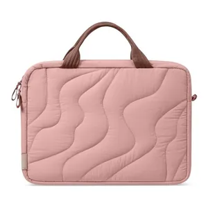 Close-up view of pink puffy laptop bag with wavy quilted texture and brown handles.