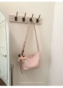 Minimalist pink shoulder bag detail, stylish hobo design with cute horse charm for women.