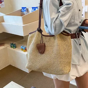 Dettaglio della grande borsa tote in paglia intrecciata con spalline in pelle marrone