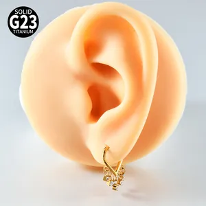 Macro detail of gold G23 titanium V-shaped earring with zircon tassels on ear model.