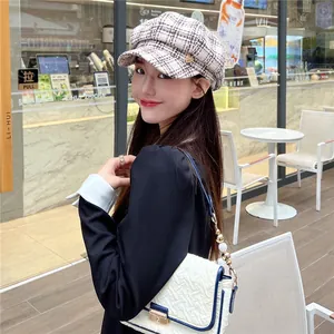 Woman wearing a vintage plaid newsboy hat with heart accent detail in a street cafe