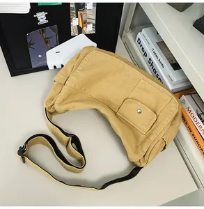 Detailed macro view of yellow canvas messenger bag with adjustable strap and snap pocket
