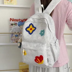 Close-up of a grey student backpack featuring colorful embroidered flower patches