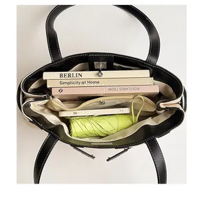 Vue intérieure du sac à bandoulière noir spacieux montrant la capacité pour livres et parapluie