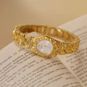 Vista detallada de un reloj de pulsera dorado Bee Sister con textura de lava sobre un libro