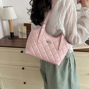 Nahaufnahme einer rosa gesteppten Lederschultertasche, getragen als Teil eines Pendler-Outfits