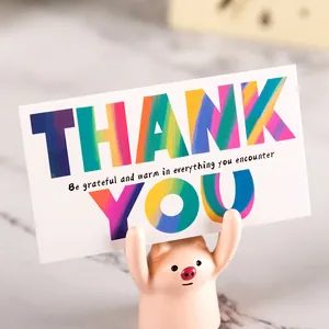 Vibrant rainbow thank you card supported by a cute pink pig desktop ornament figurine