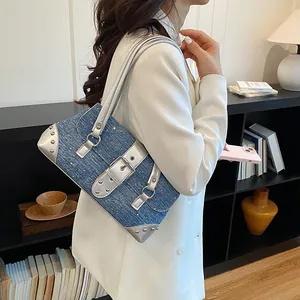 Side view of a trendy blue denim underarm bag with silver buckle worn by a model