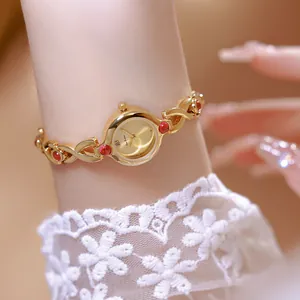 Vista detallada de un reloj de mujer vintage dorado con piedras rojas y encaje elegante
