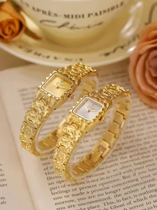 Detalle de elegantes relojes de pulsera vintage dorados con textura de lava sobre un libro