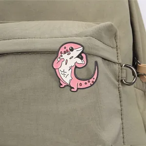 Nahaufnahme eines lustigen Muskel-Echsen-Emaille-Pins an einem grünen Canvas-Rucksack.