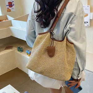Vista posteriore di una grande borsa tote in paglia intrecciata con manici marroni